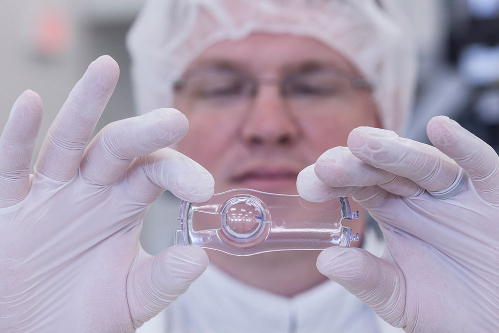 Close up of an engineer in safety gear holding a tool towards the camera